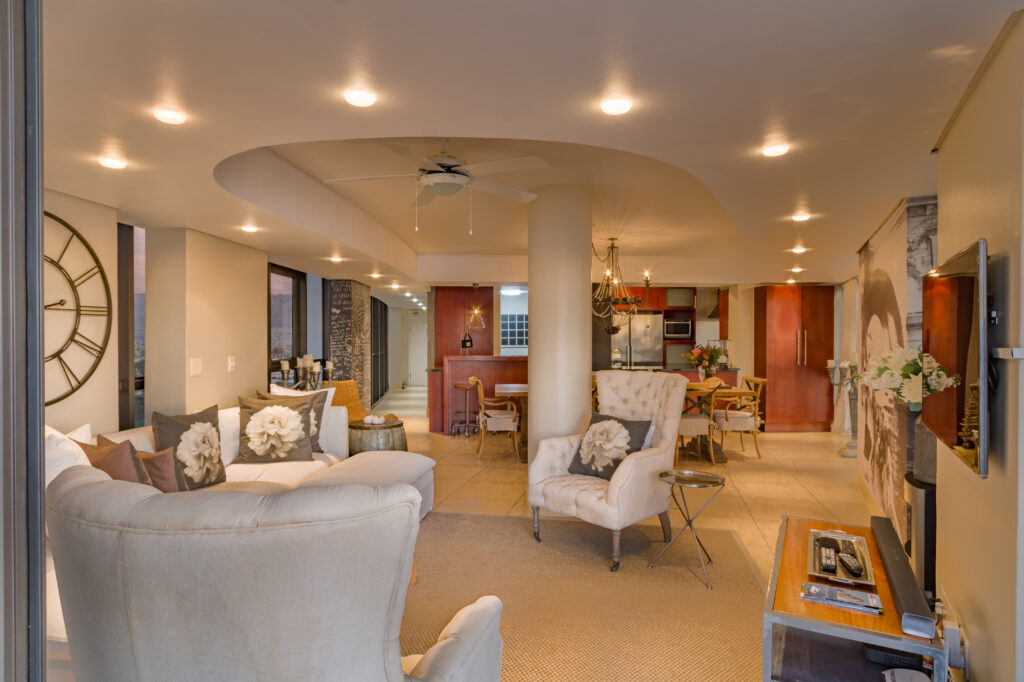Warmly lit open-plan lounge, dining area and kitchen at Ocean View Apartment in Strand