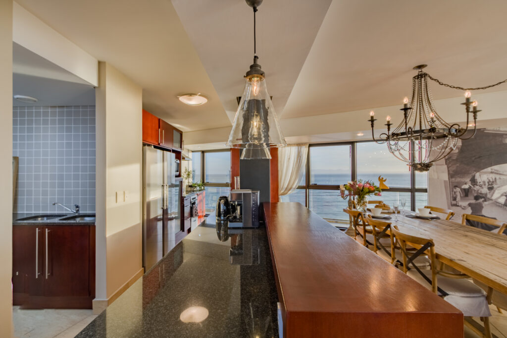 Pendant lights above the kitchen counter and dining table overlooking the sea at Ocean View Apartment